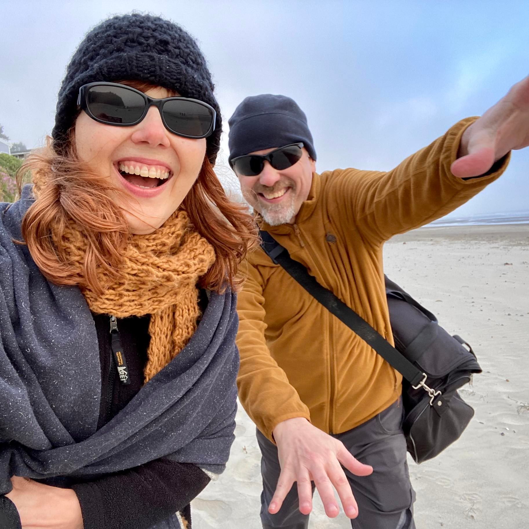 A man and a woman are posing for a picture on the beach