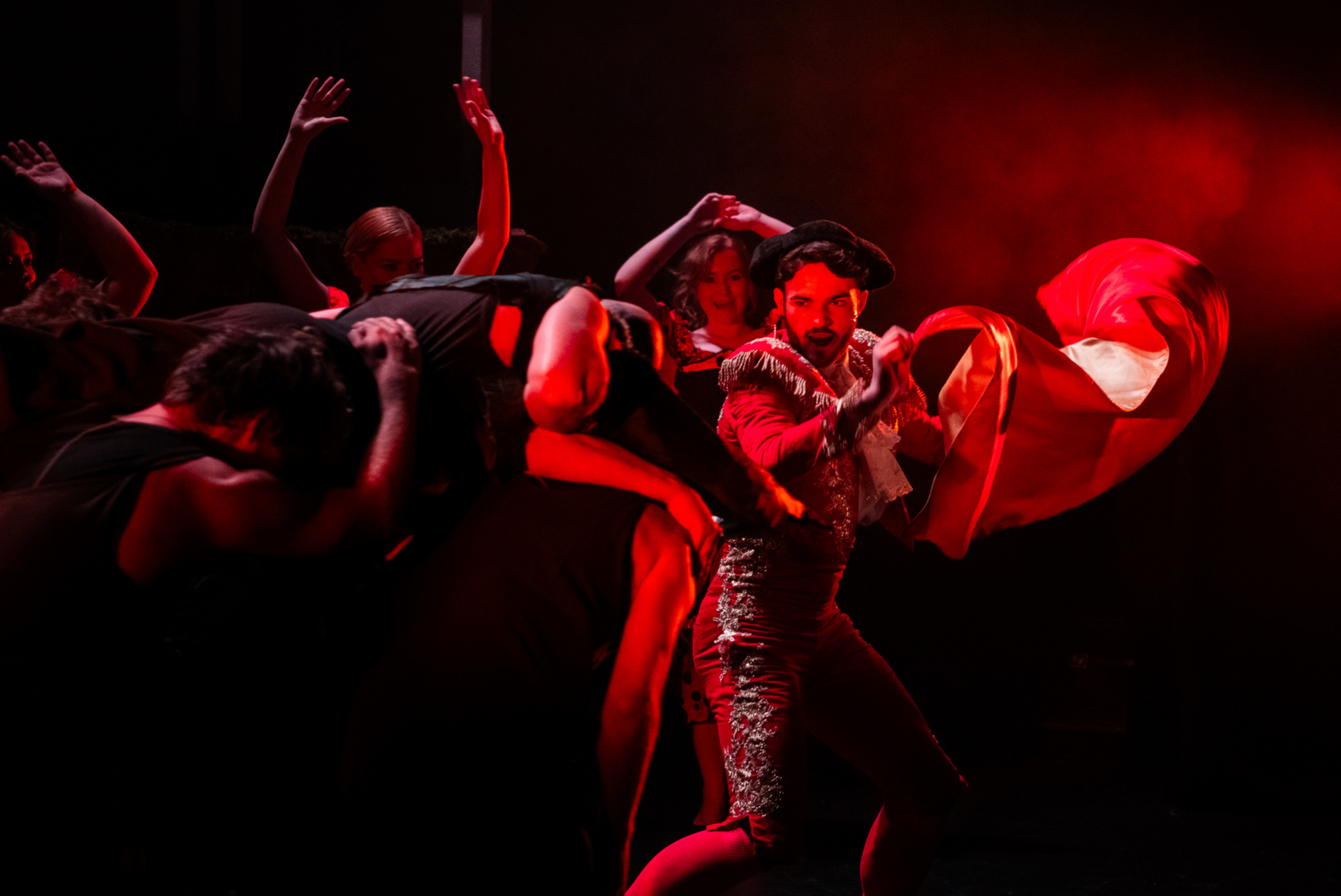 A group of people are dancing on a stage in a dark room.