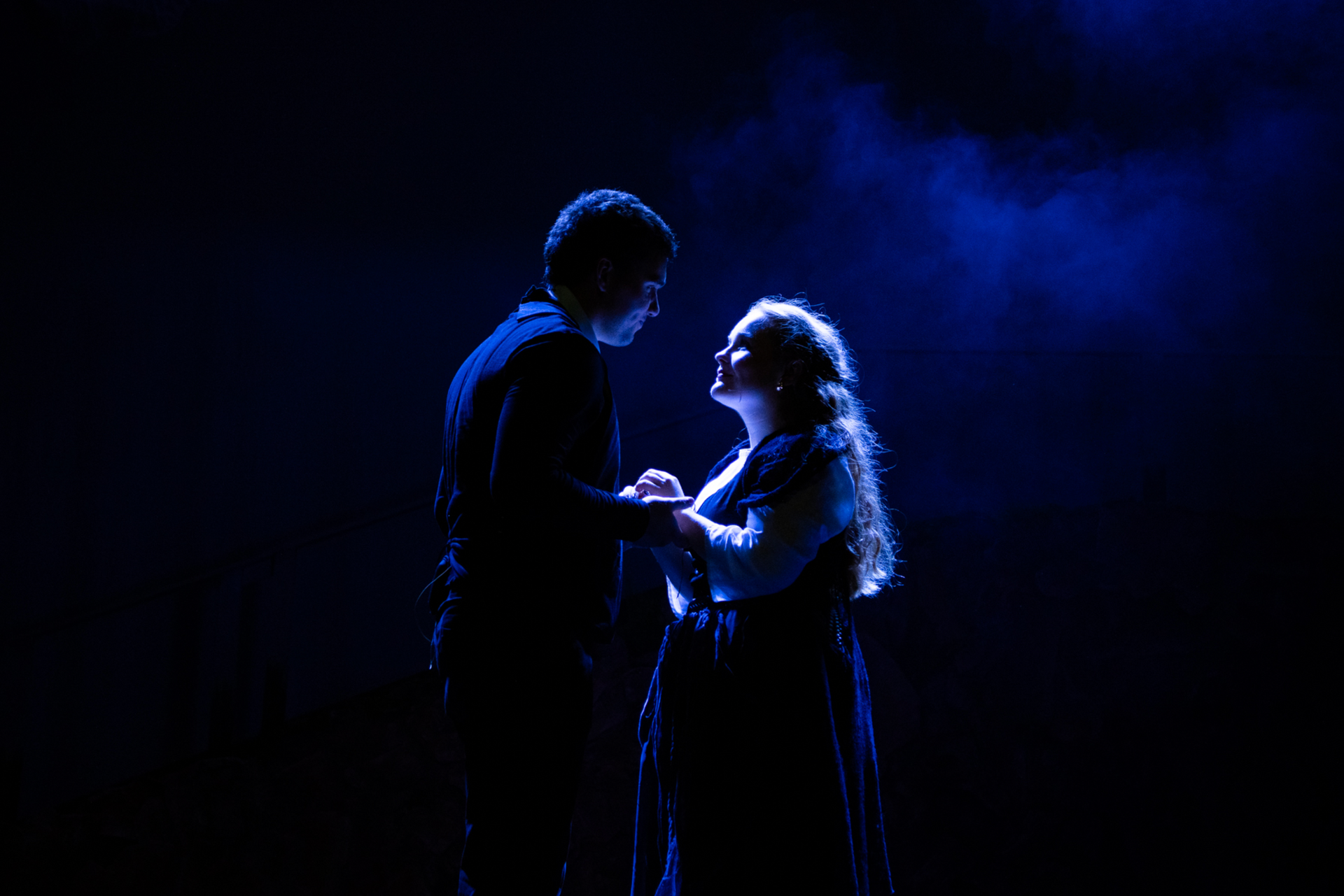 A man and a woman are standing next to each other on a stage holding hands.