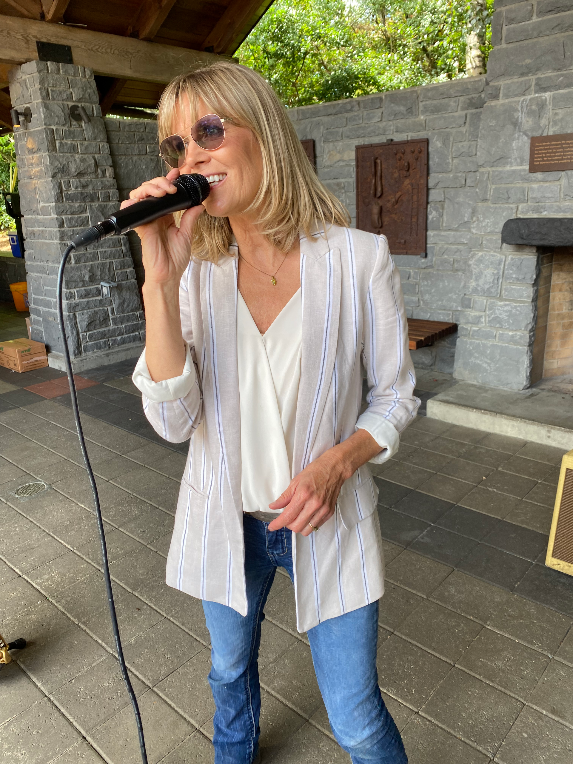 A woman in a white jacket is singing into a microphone.