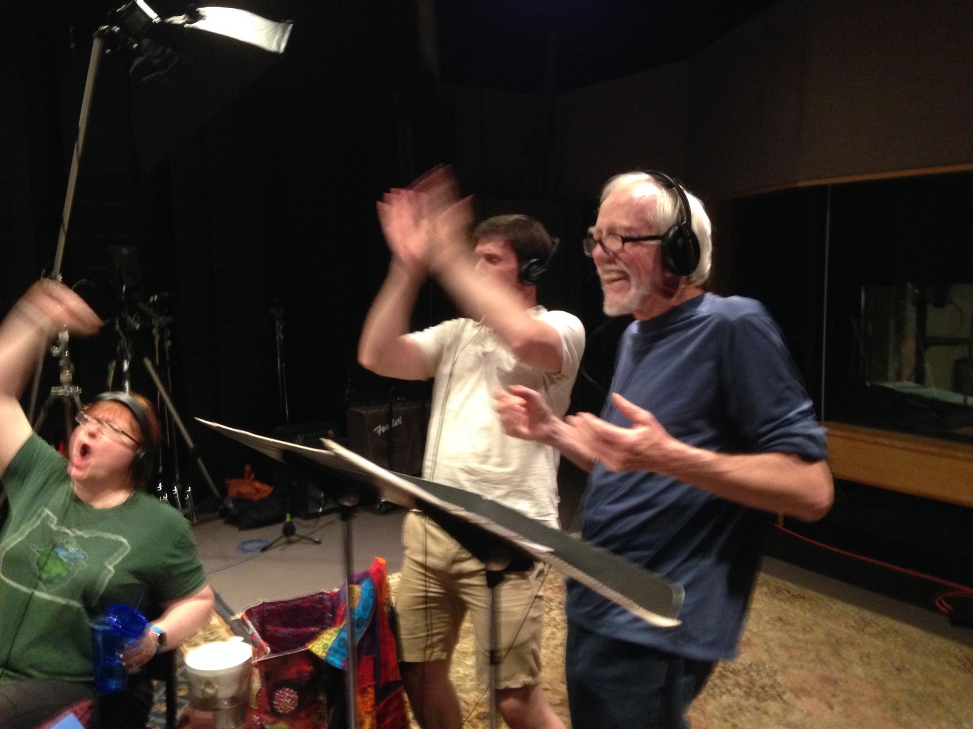 A group of people are singing in a recording studio
