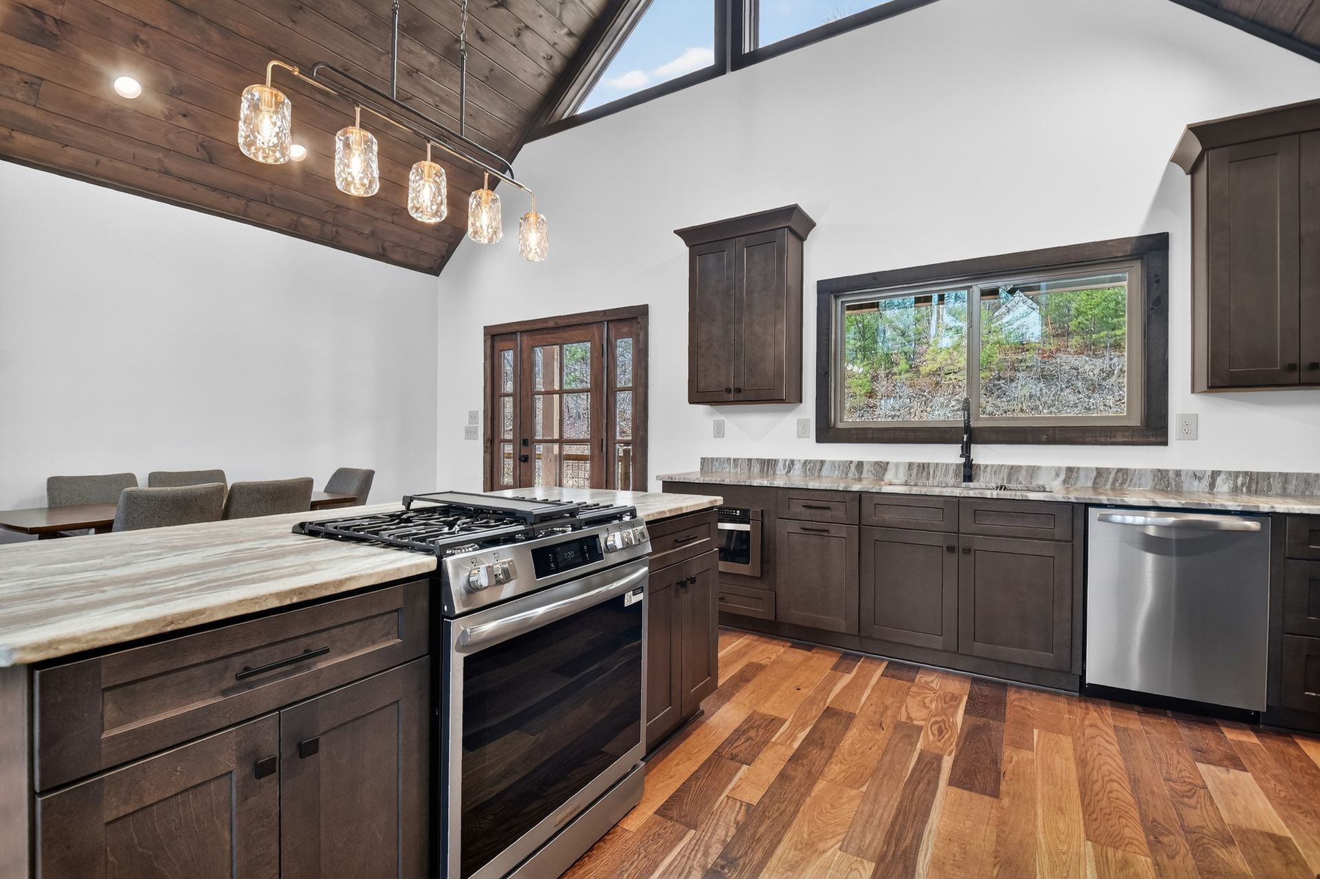 Modern kitchen with dark wood cabinets, granite island, hardwood floors, and large windows