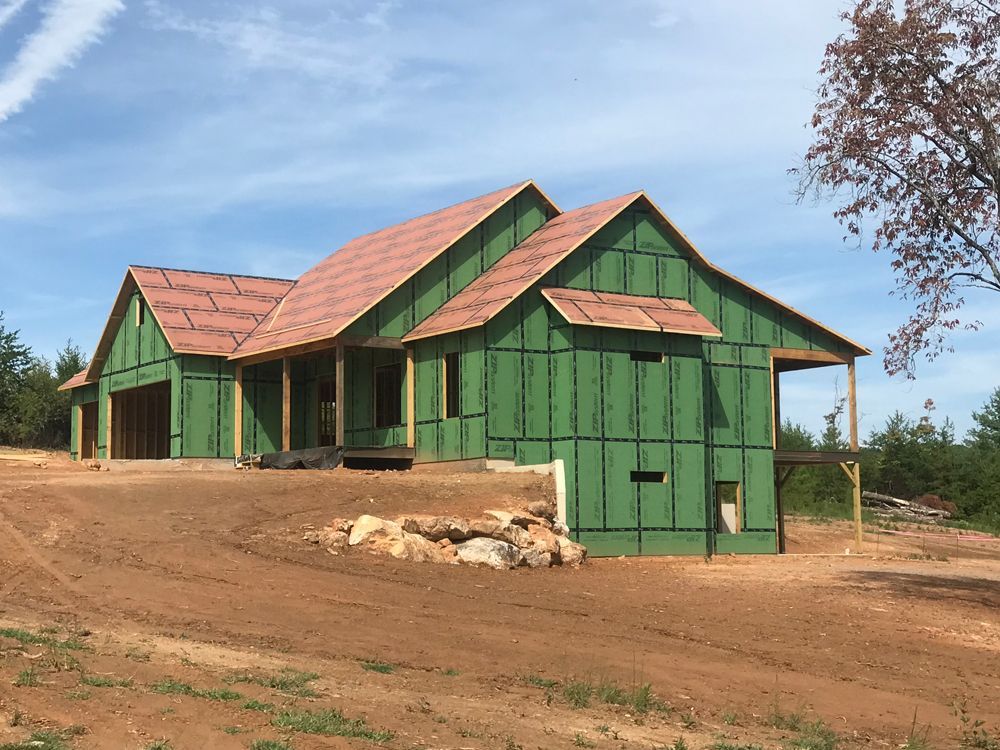A house under construction with green siding and a red roof