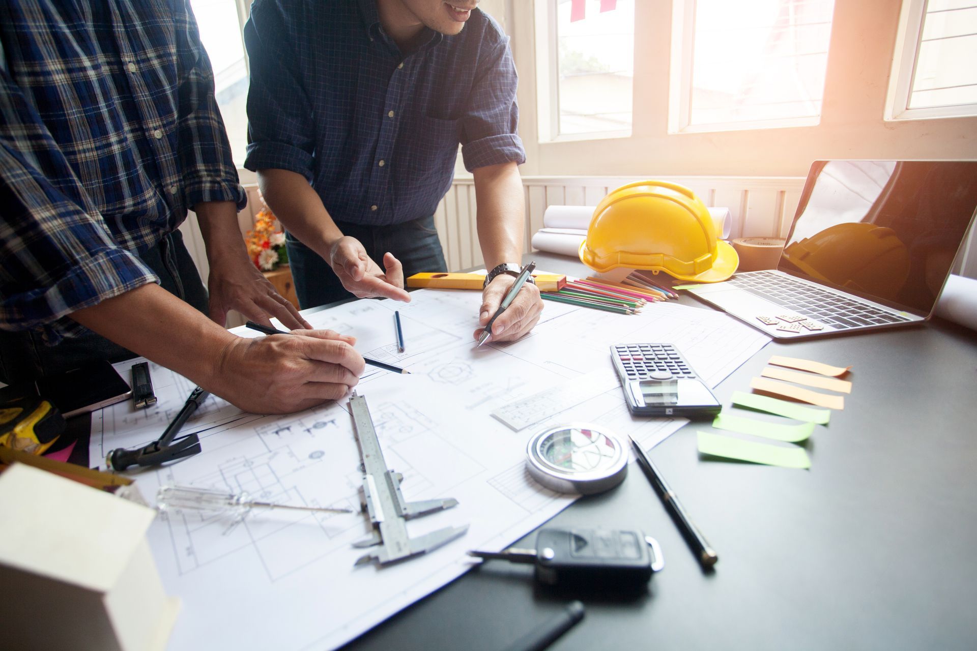 Two men are looking at a blueprint on a table.