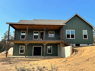 A large green house is sitting on top of a dirt hill.