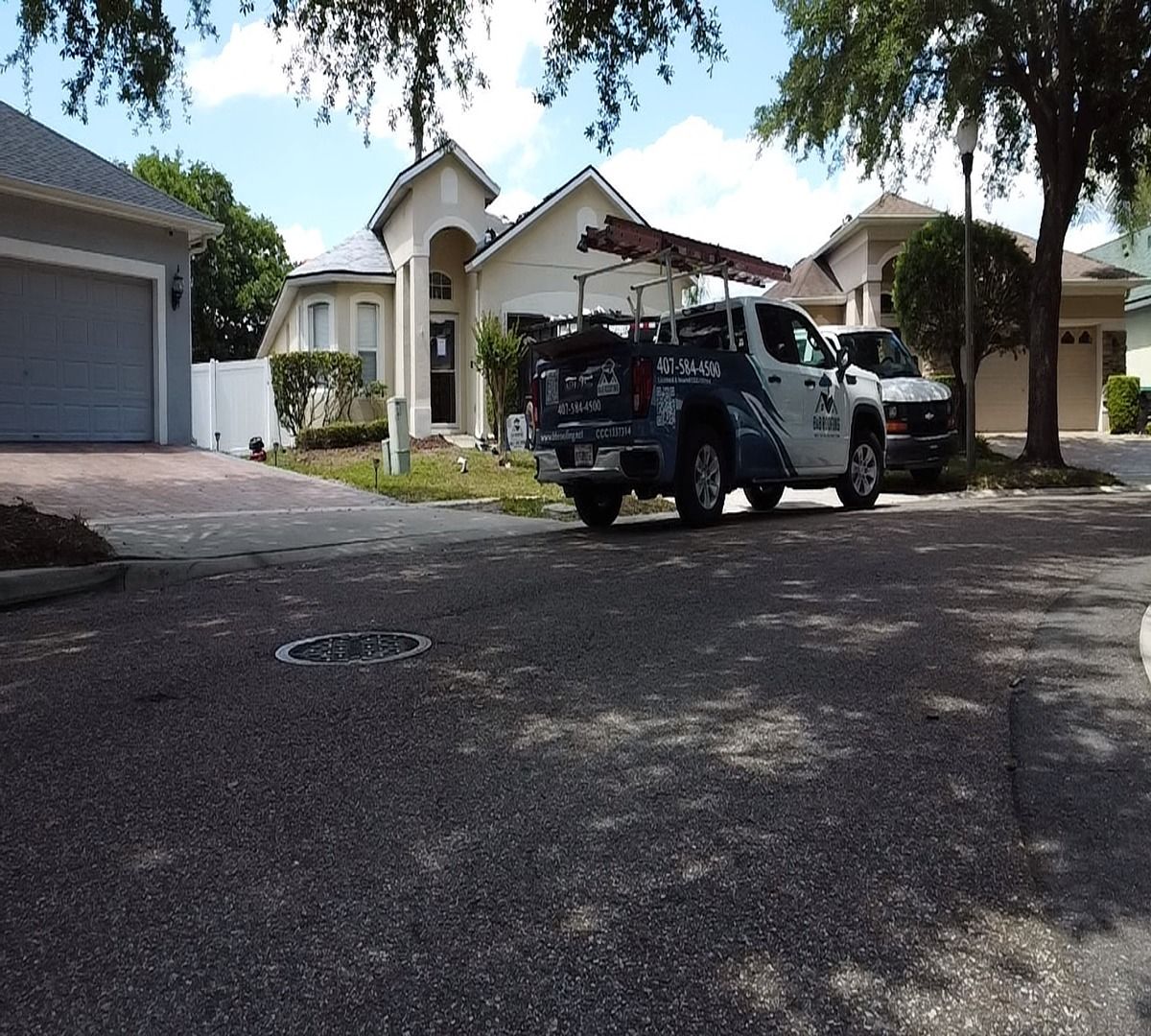 Two parked SUVs in a driveway before a white house with a garage and palm trees
