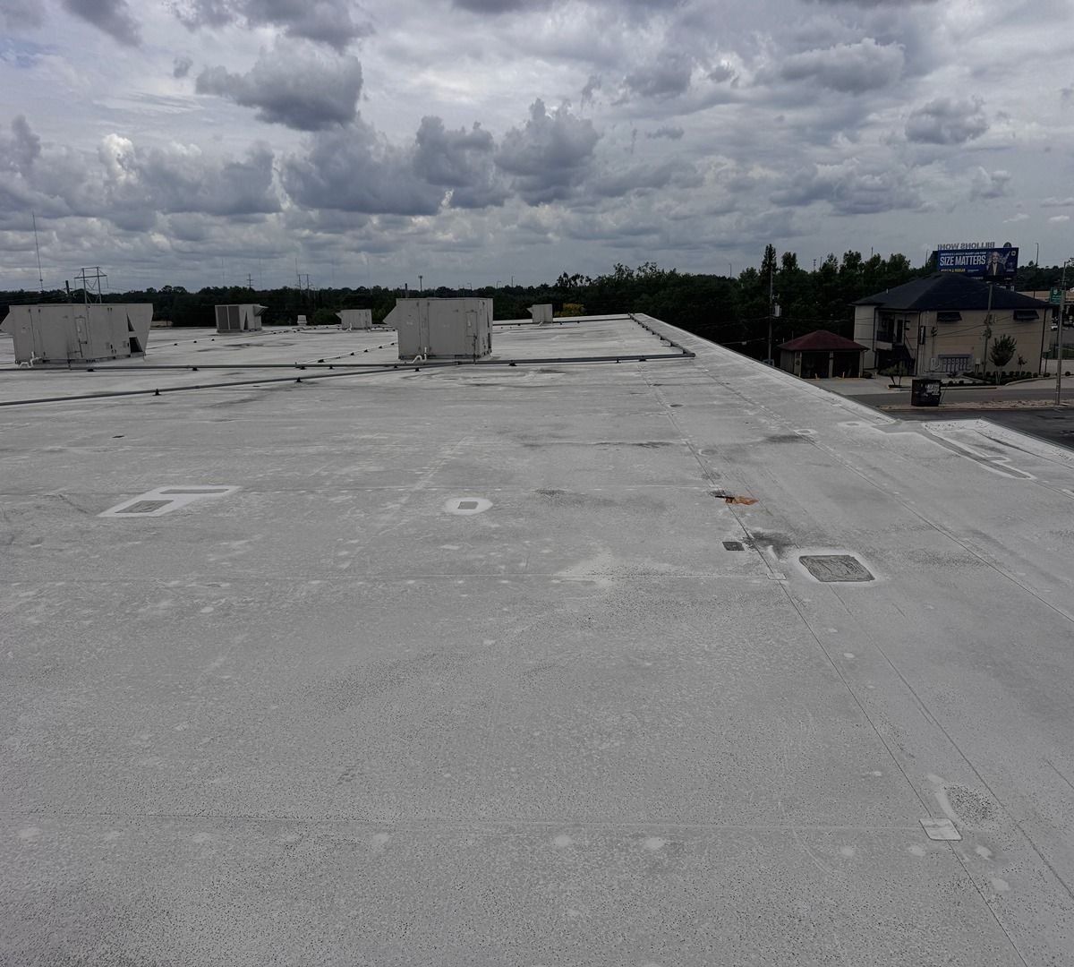 Flat white rooftop under cloudy skies, with vents and distant buildings along the horizon.