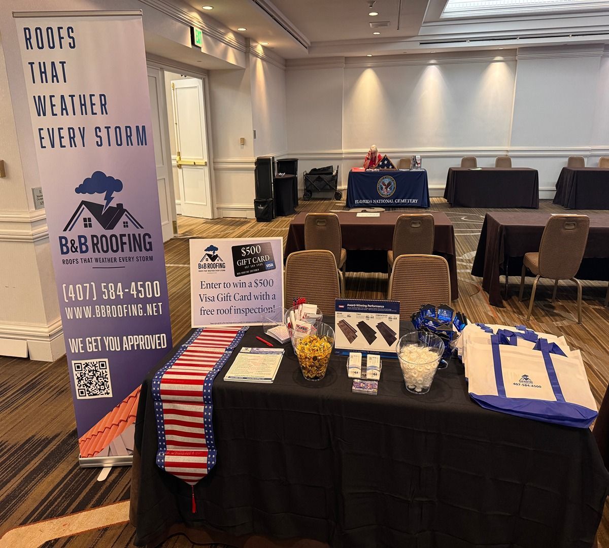 Booth with B&B Roofing banner, flyers, and striped ties at an indoor expo table
