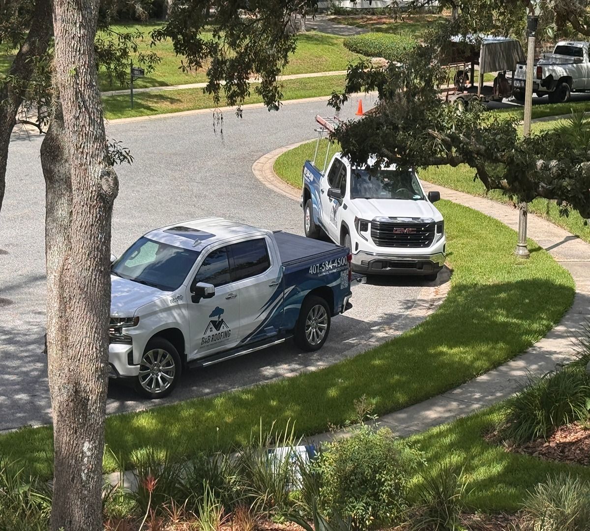 Two pickup trucks parked on a curved driveway beside a grassy lawn and trees.