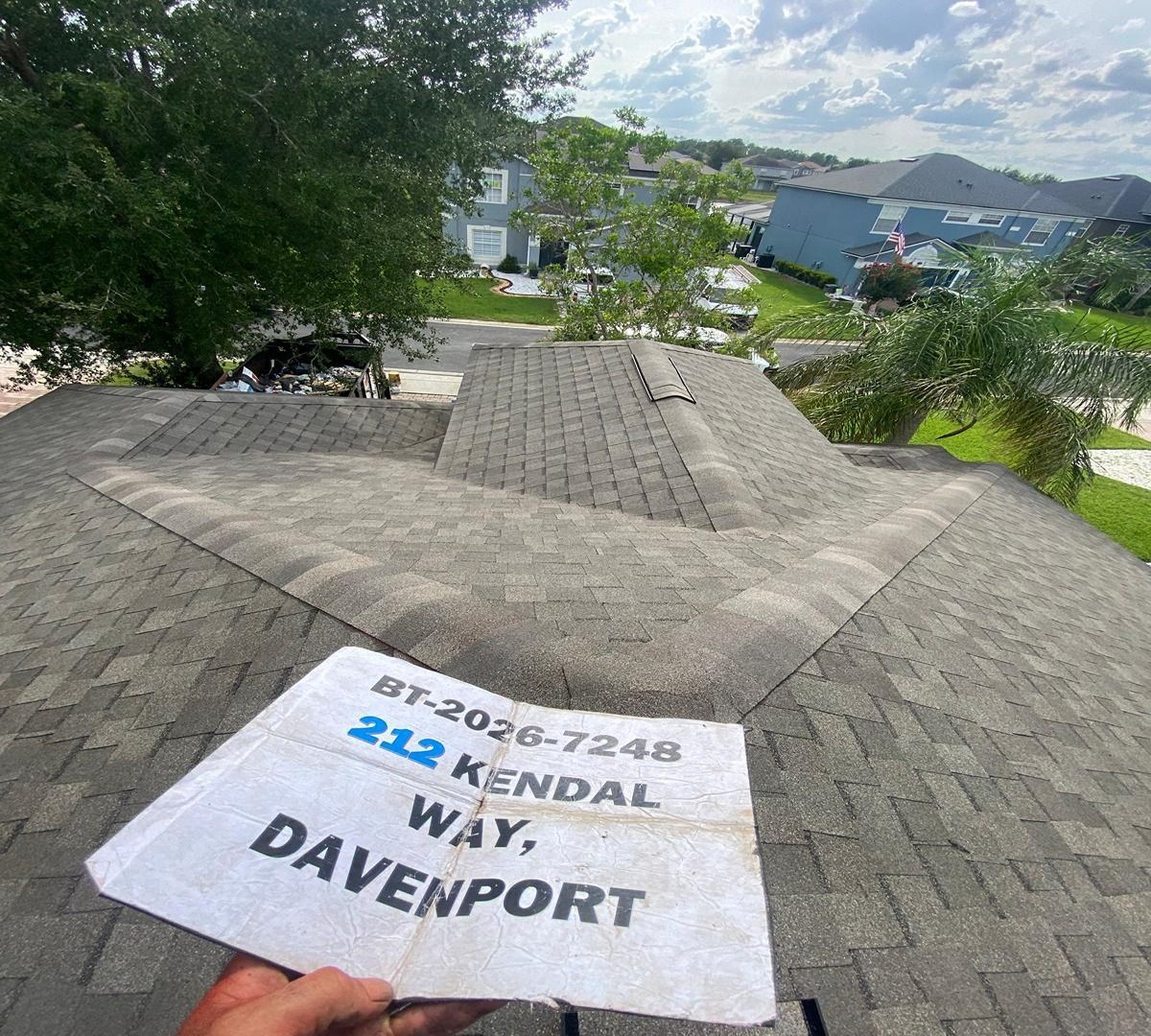 Hand holding a “Way, Davenport” sign overlooking rooftops and greenery on a sunny day