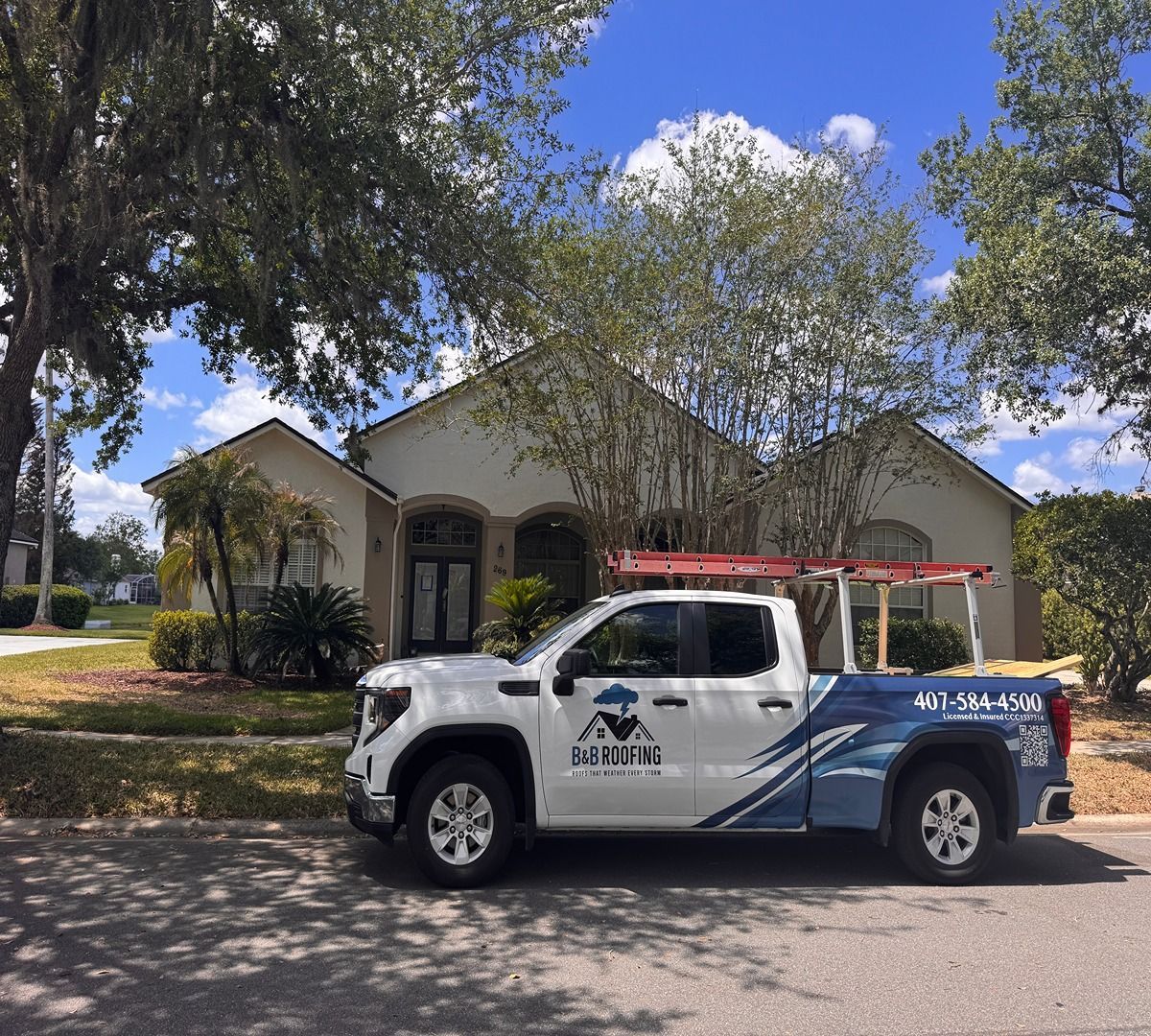 White utility pickup truck parked in front of a beige house under trees on a sunny street