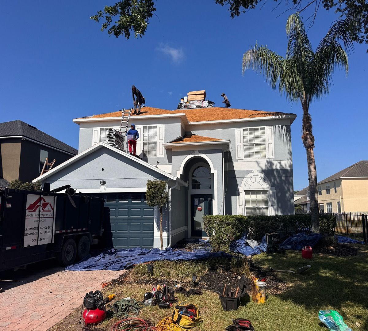 Damaged two-story house with debris in the yard and a truck parked in the driveway after a storm