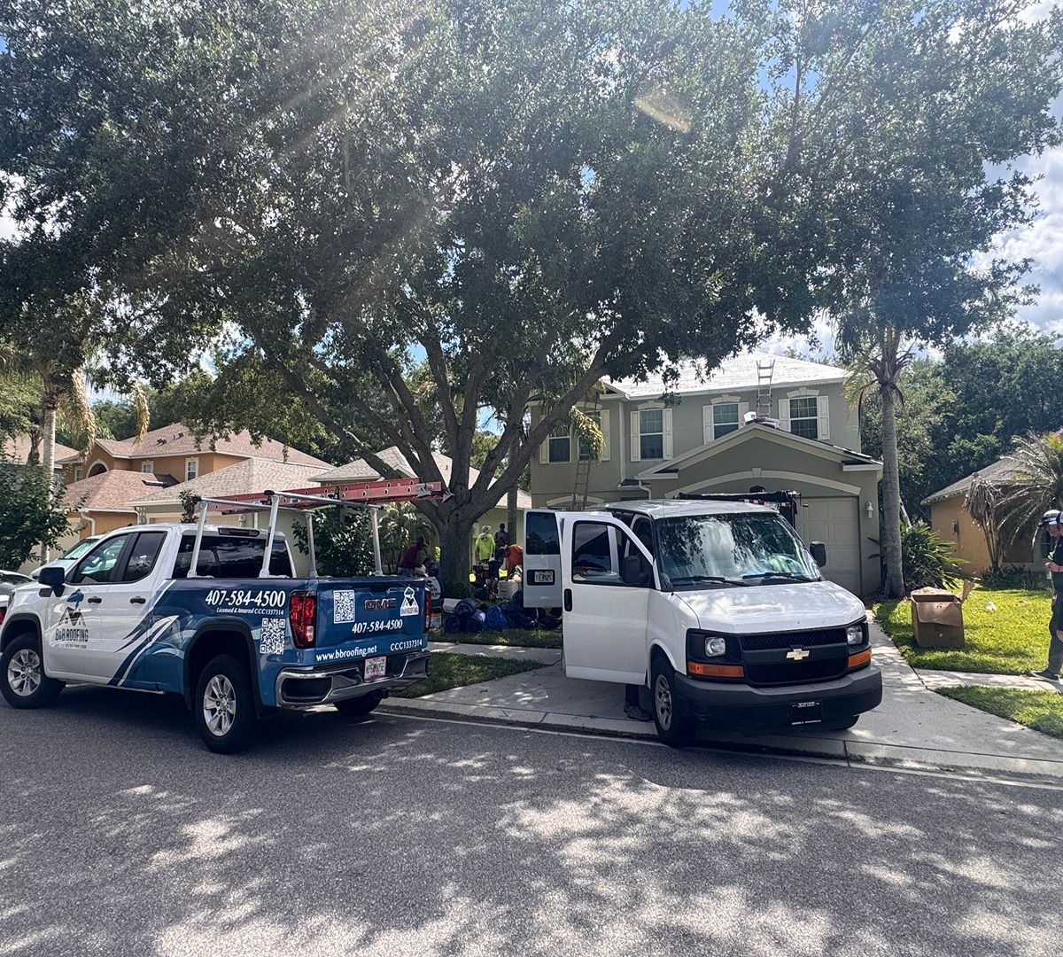 Two parked work trucks on a tree-lined residential street in front of houses