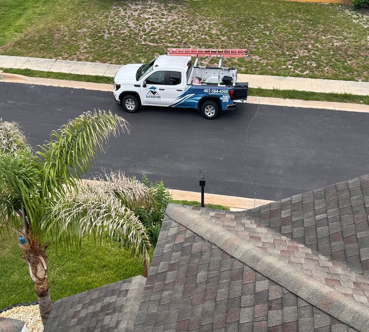 White utility truck parked on a residential street beside a lawn, seen from above.