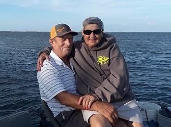 Two people sitting together on a boat, smiling on the open water.