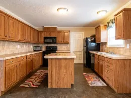 Spacious kitchen with oak cabinets, black appliances, and a central island under warm ceiling lights