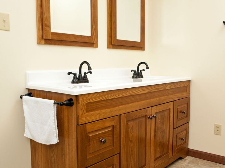 Wooden double-sink bathroom vanity with white countertop, black faucets, and wall mirrors.