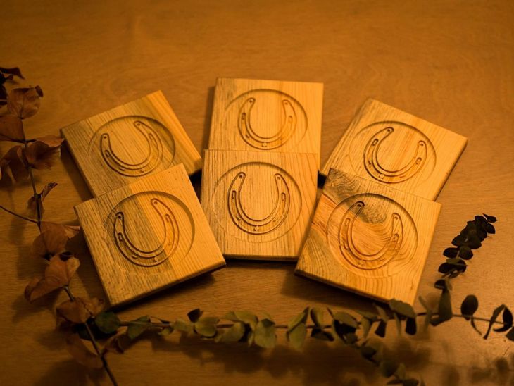 Three wooden blocks with circular line drawings on a warm brown surface, framed by dried leaves and vines