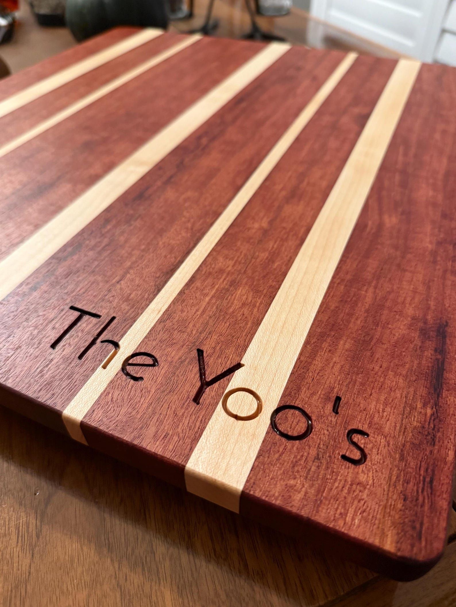 Wooden cutting board with light and dark stripes and handwritten text reading “The Zoo’s”