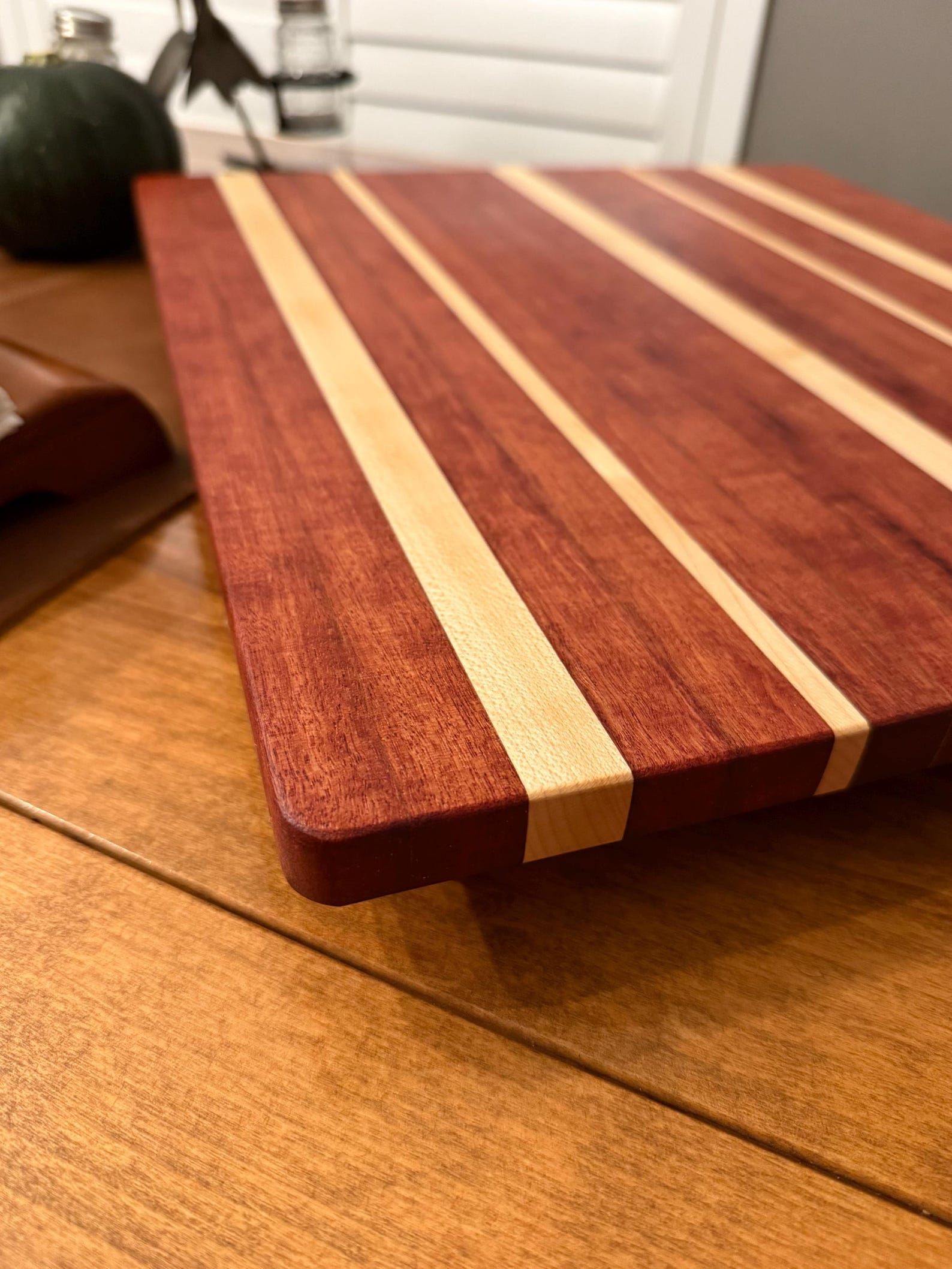 Wooden cutting board with dark and light striped wood grain on a table