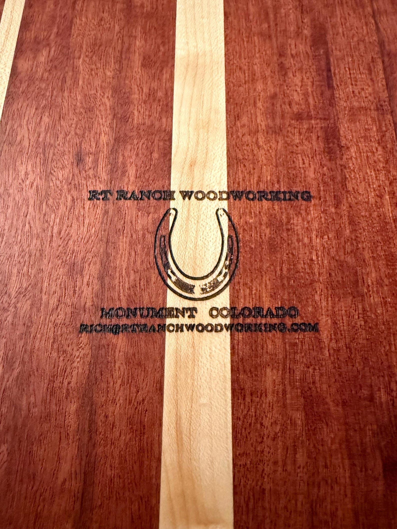 Wooden plaque with a centered horseshoe and engraved text on a light stripe