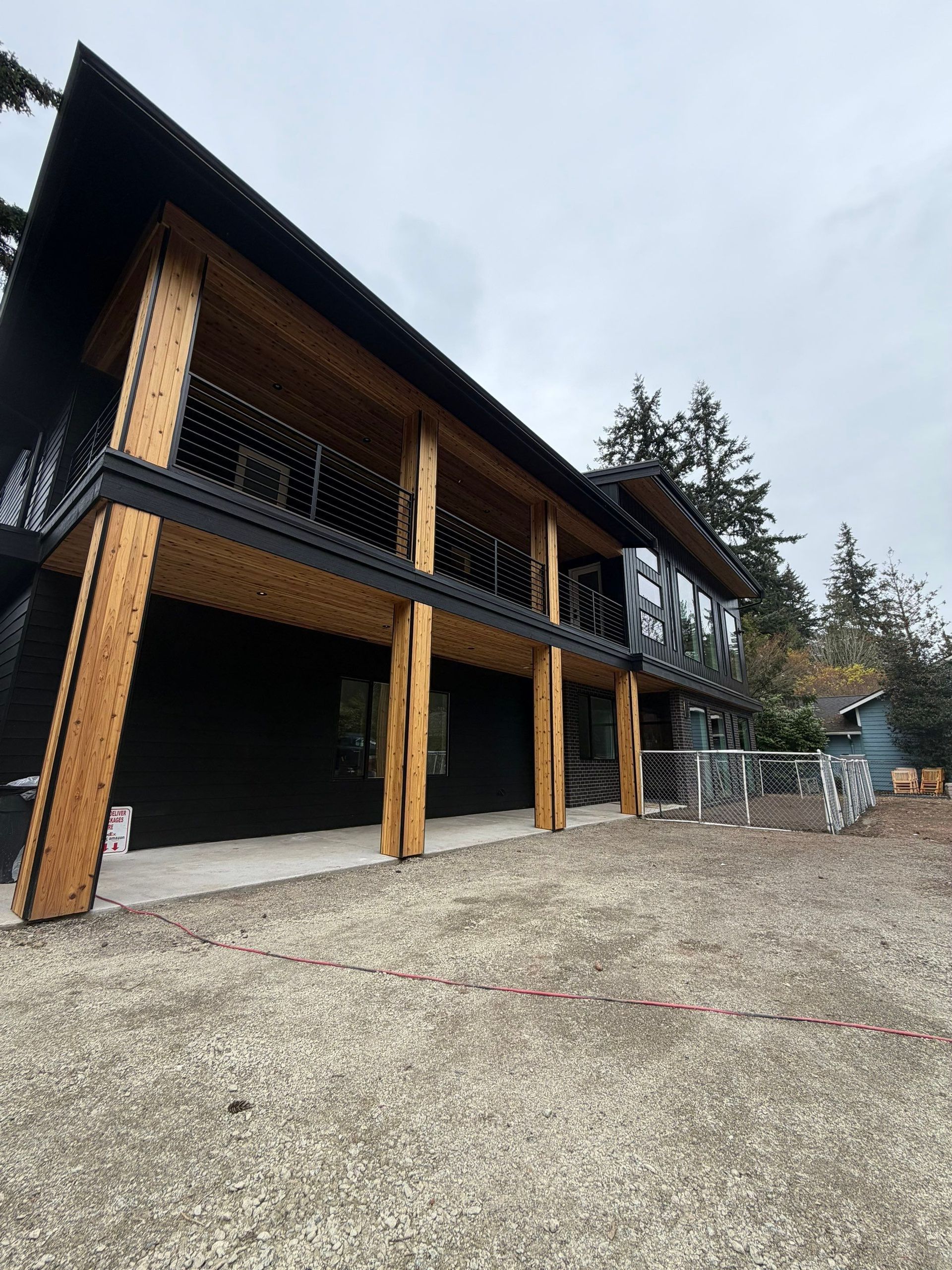 Modern two-story beige house with black trim, centered front door, and landscaped walkway