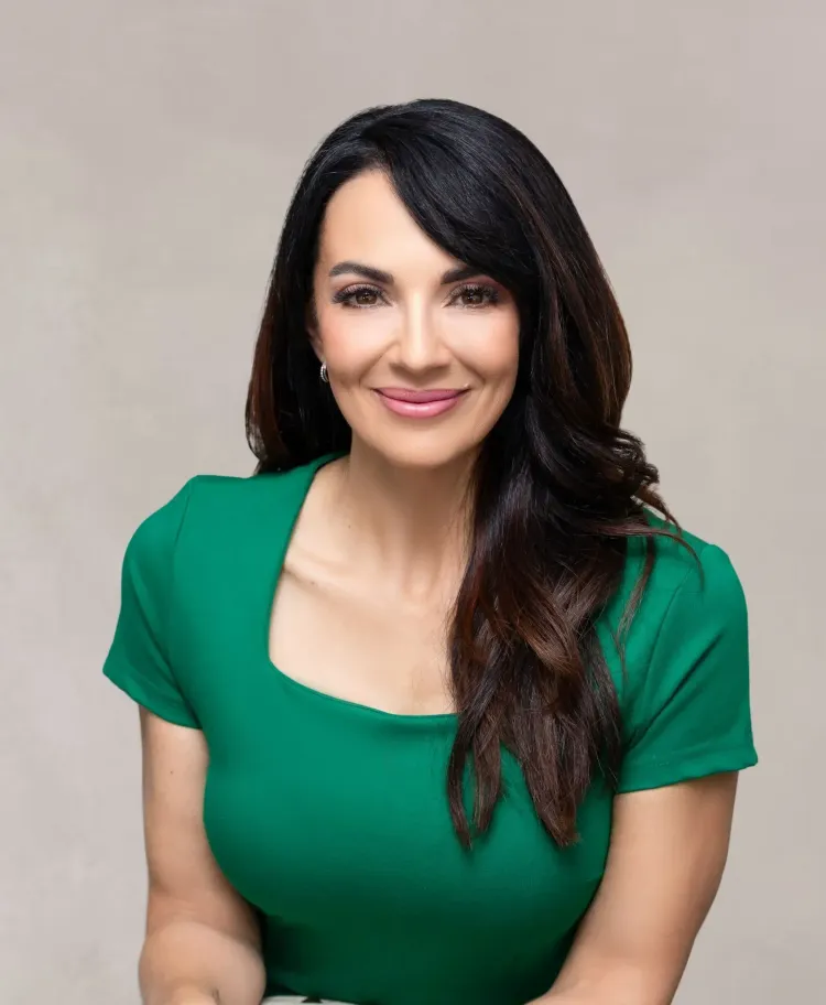 Portrait of a smiling woman in a green top against a neutral background