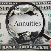 Magnifying glass over the word “Annuities” on a U.S. dollar bill background
