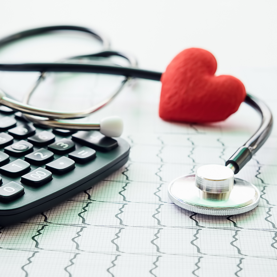 Stethoscope, calculator, eyeglasses, and red heart on a medical chart, symbolizing healthcare finances