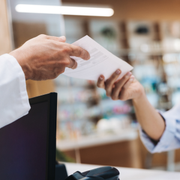 Hands exchanging a white card at a store counter, with a blurred retail background.