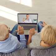 Couple on a couch having a video call with a doctor on a laptop