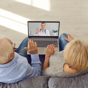 Couple on a couch having a video call with a doctor on a laptop