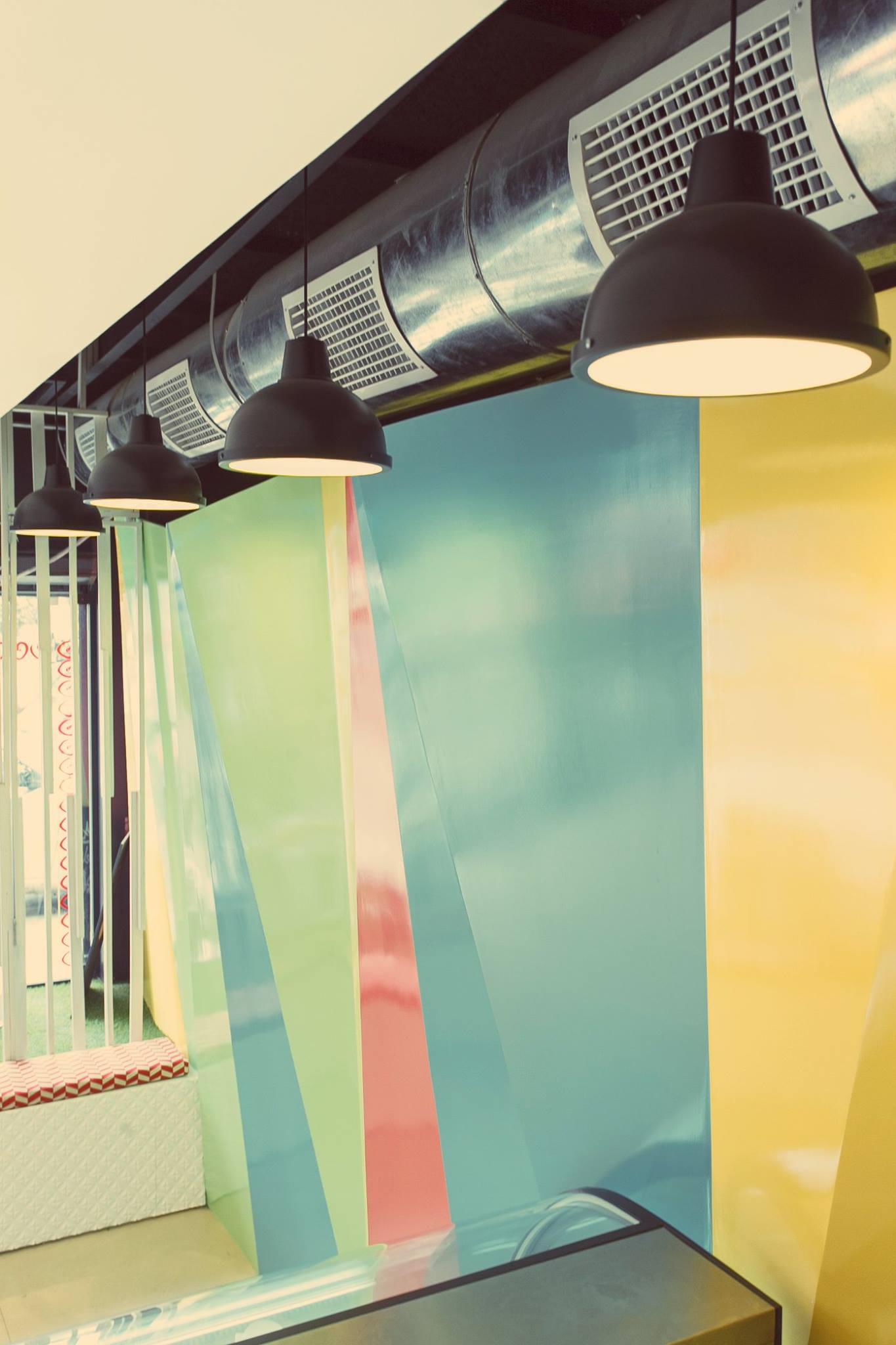 Una hilera de lámparas colgando del techo frente a una pared colorida.