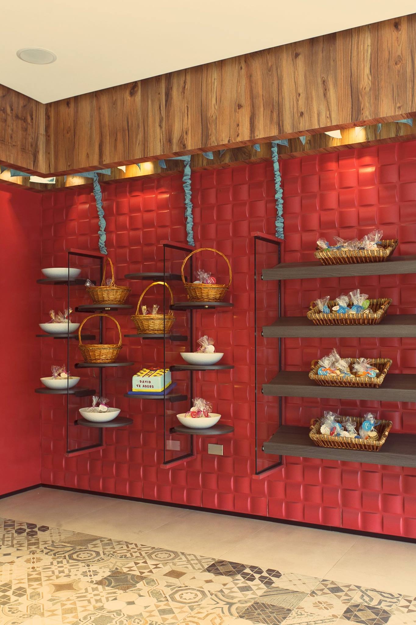 Una habitación con una pared roja y estantes llenos de cestas y cuencos.