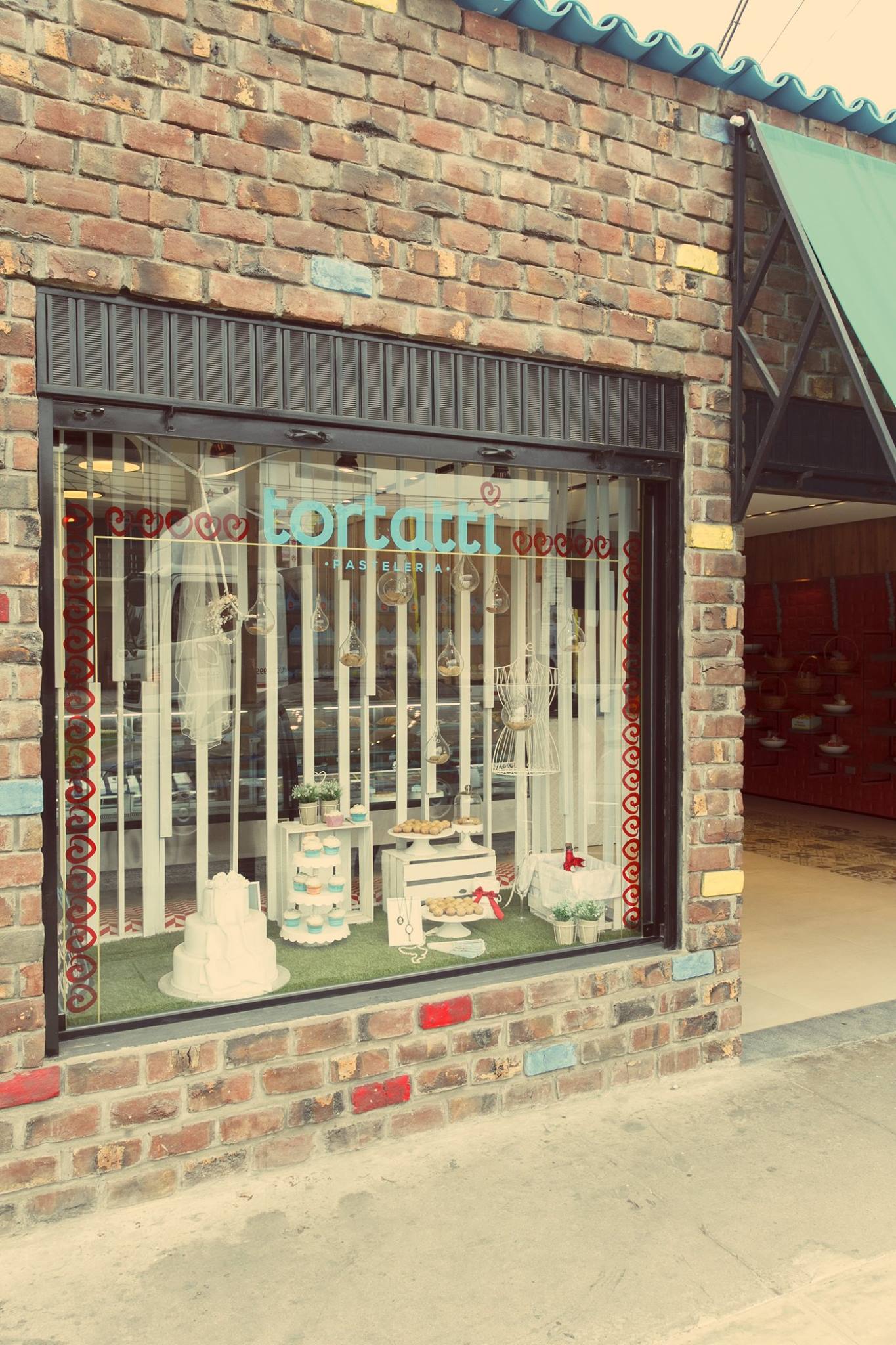 Un edificio de ladrillos con un escaparate con pasteles y velas.
