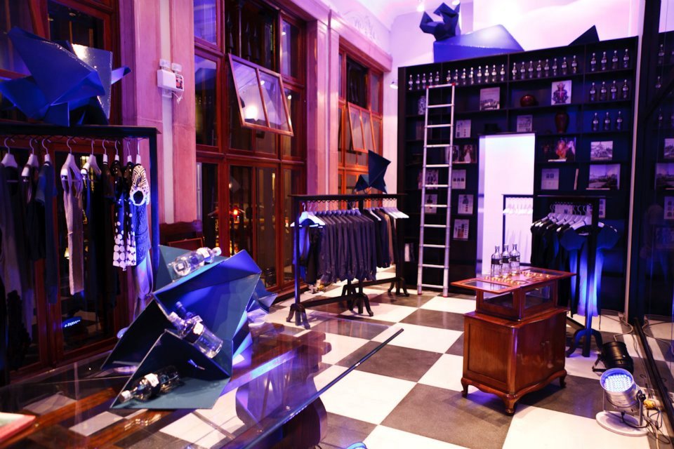 Una tienda con suelo cuadriculado y ropa colgada en perchas.