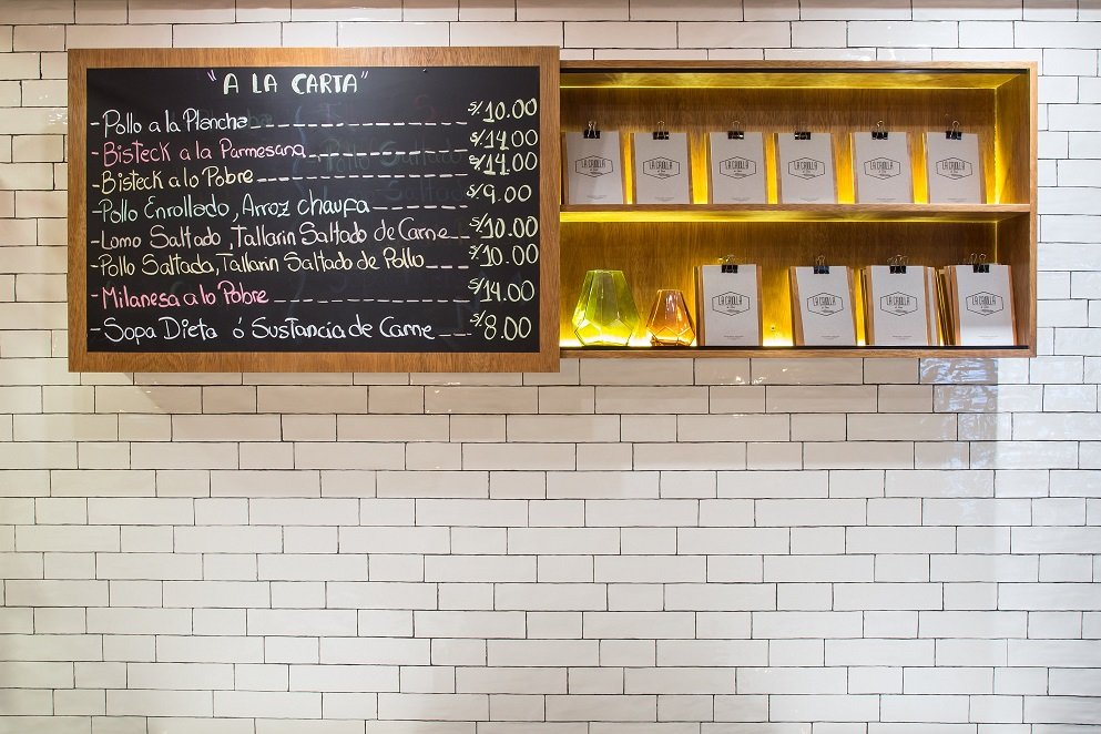 Una pizarra en una pared de ladrillos blancos tiene un menú.