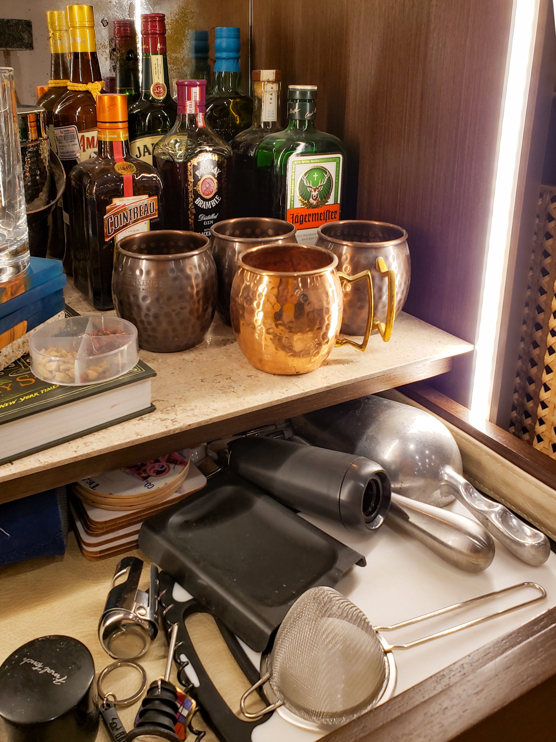 Un estante lleno de botellas, tazas y otros artículos.