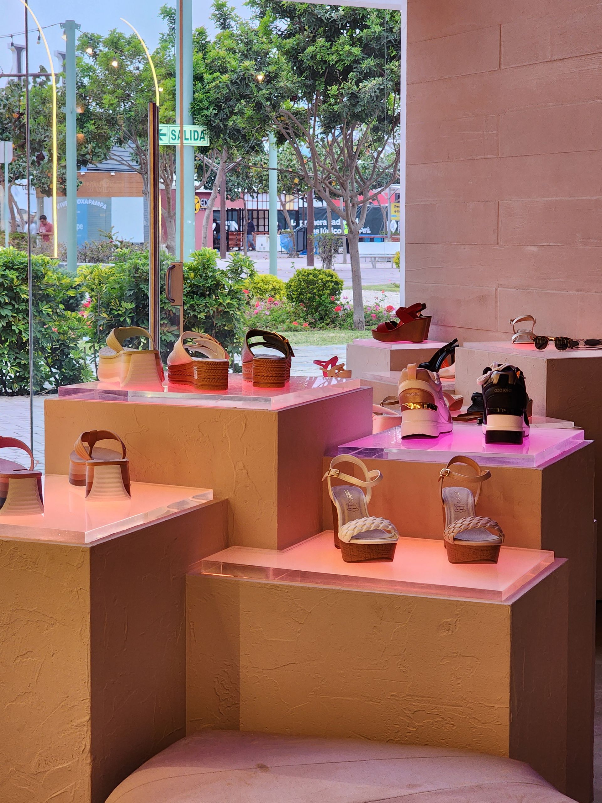 Una exhibición de zapatos en una tienda con una ventana al fondo.