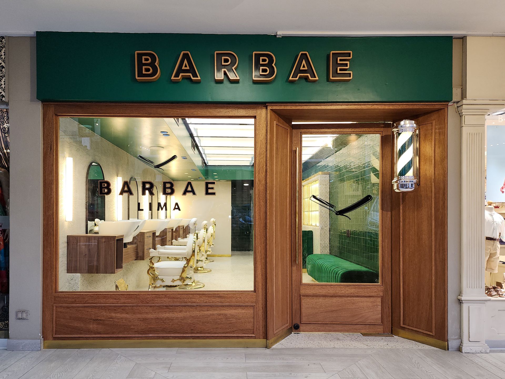 El frente de una barbería con un cartel verde y un poste de barbero.