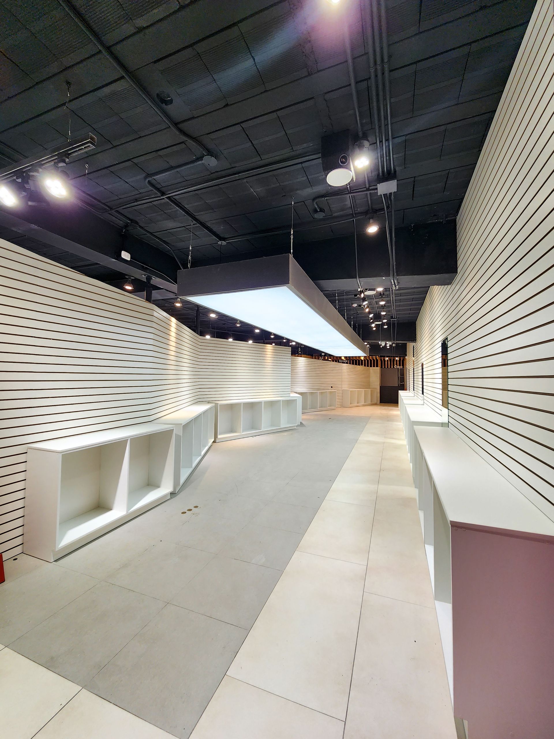 Un pasillo largo con muchos estantes y una luz de techo.