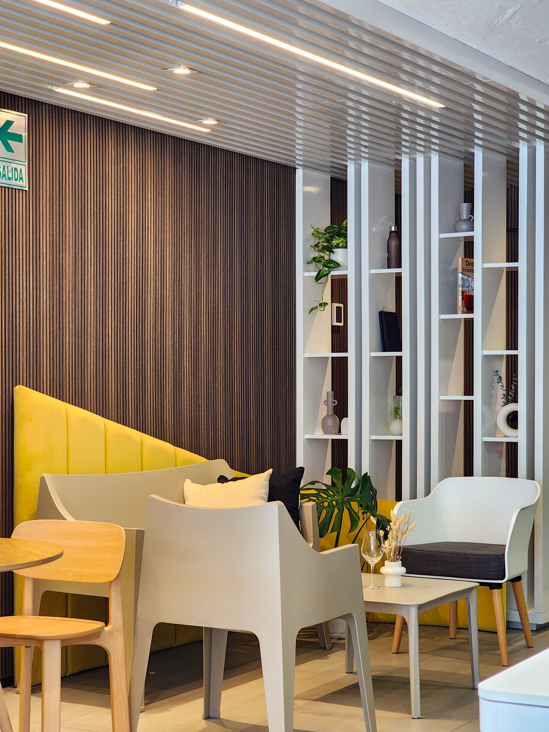 Una sala de estar con sofá, sillas, mesas y estanterías.