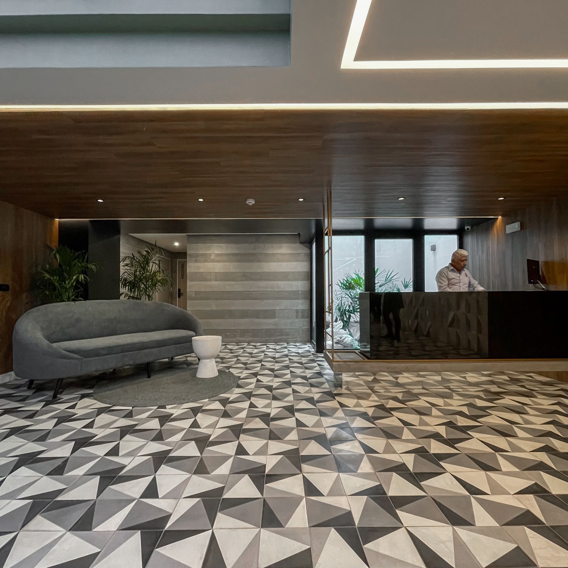 Un hombre está de pie frente a un mostrador en un vestíbulo con un sofá.