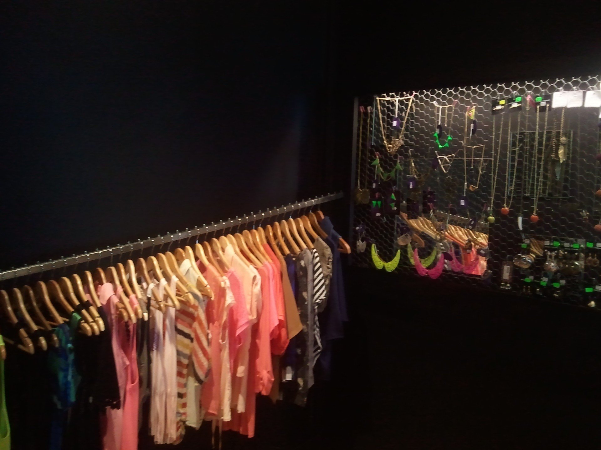 Un montón de ropa está colgada en un perchero en una habitación oscura.