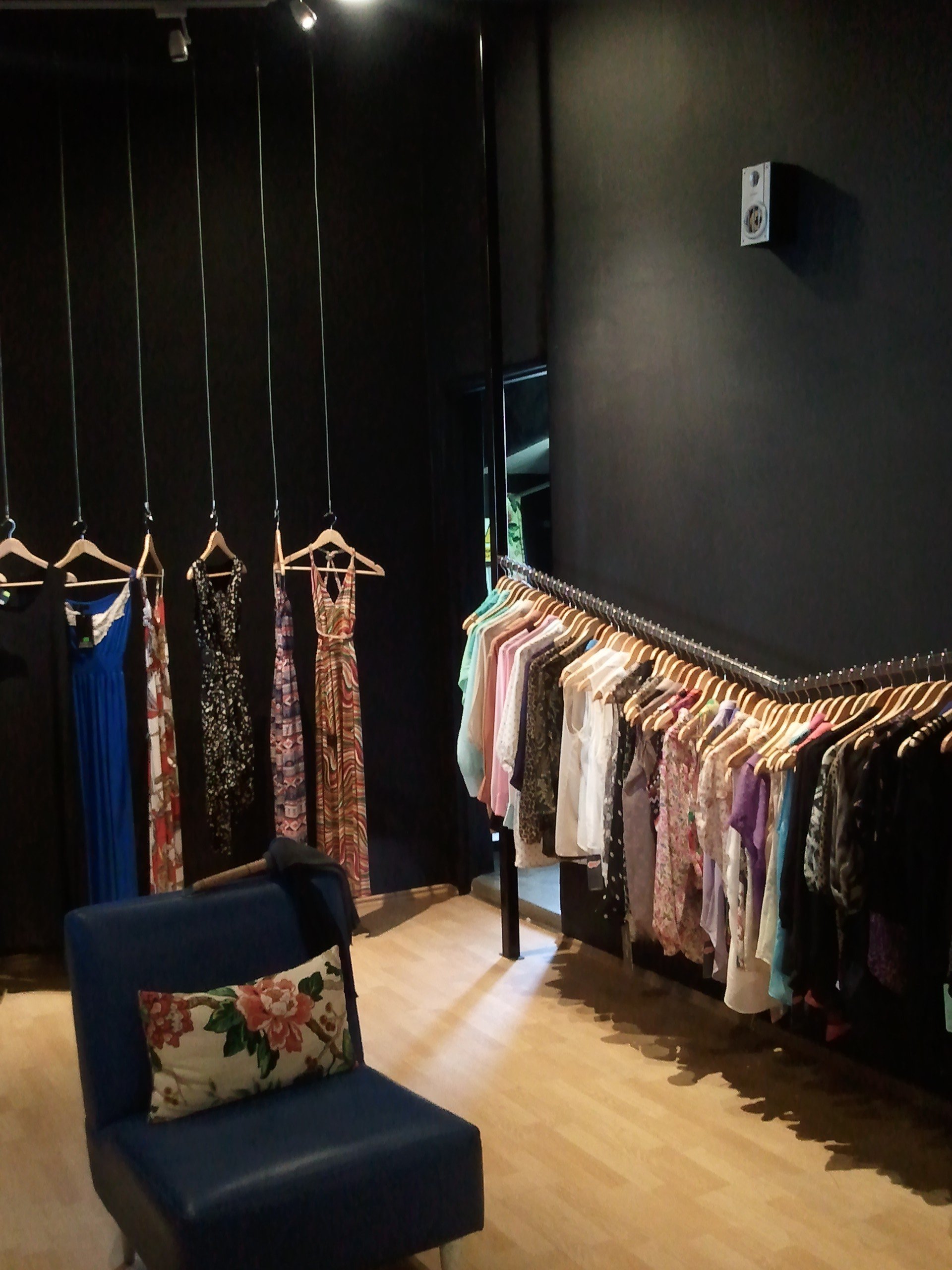 Una habitación con ropa colgada en percheros y una silla.