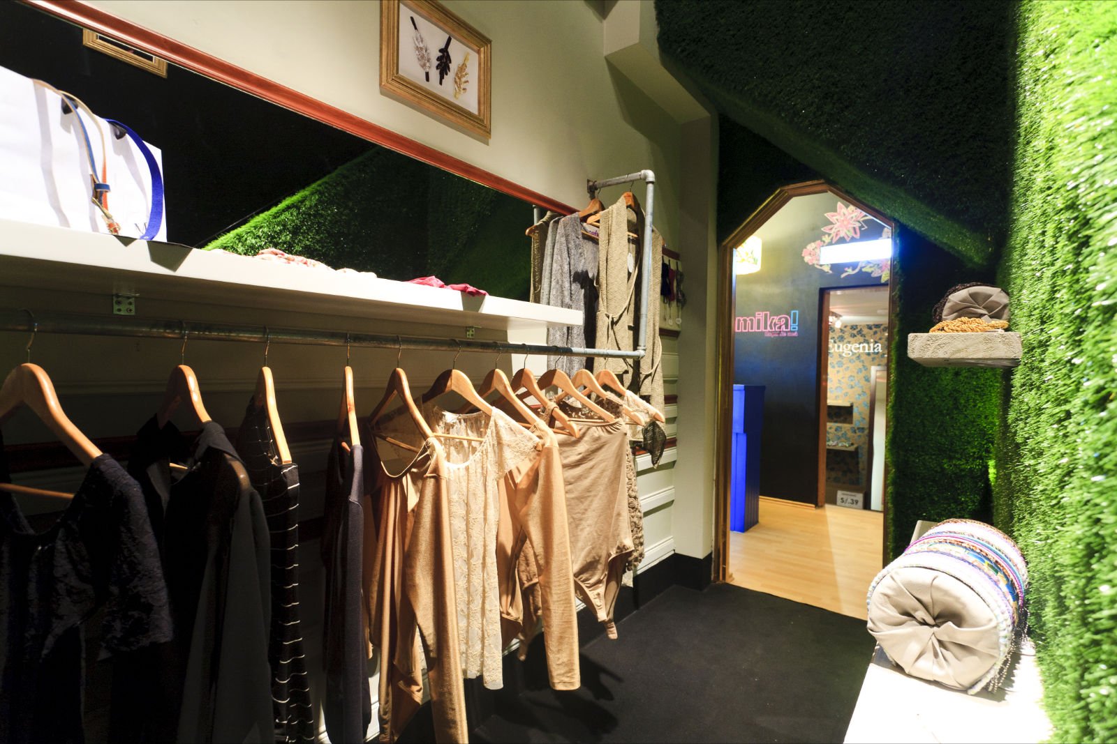 Un armario con ropa colgada en perchas y una pared verde.