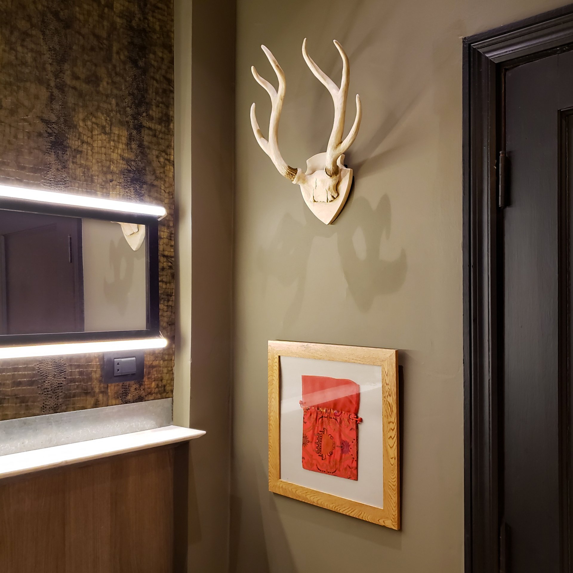 Una imagen de una cabeza de ciervo cuelga en una pared al lado de un espejo.