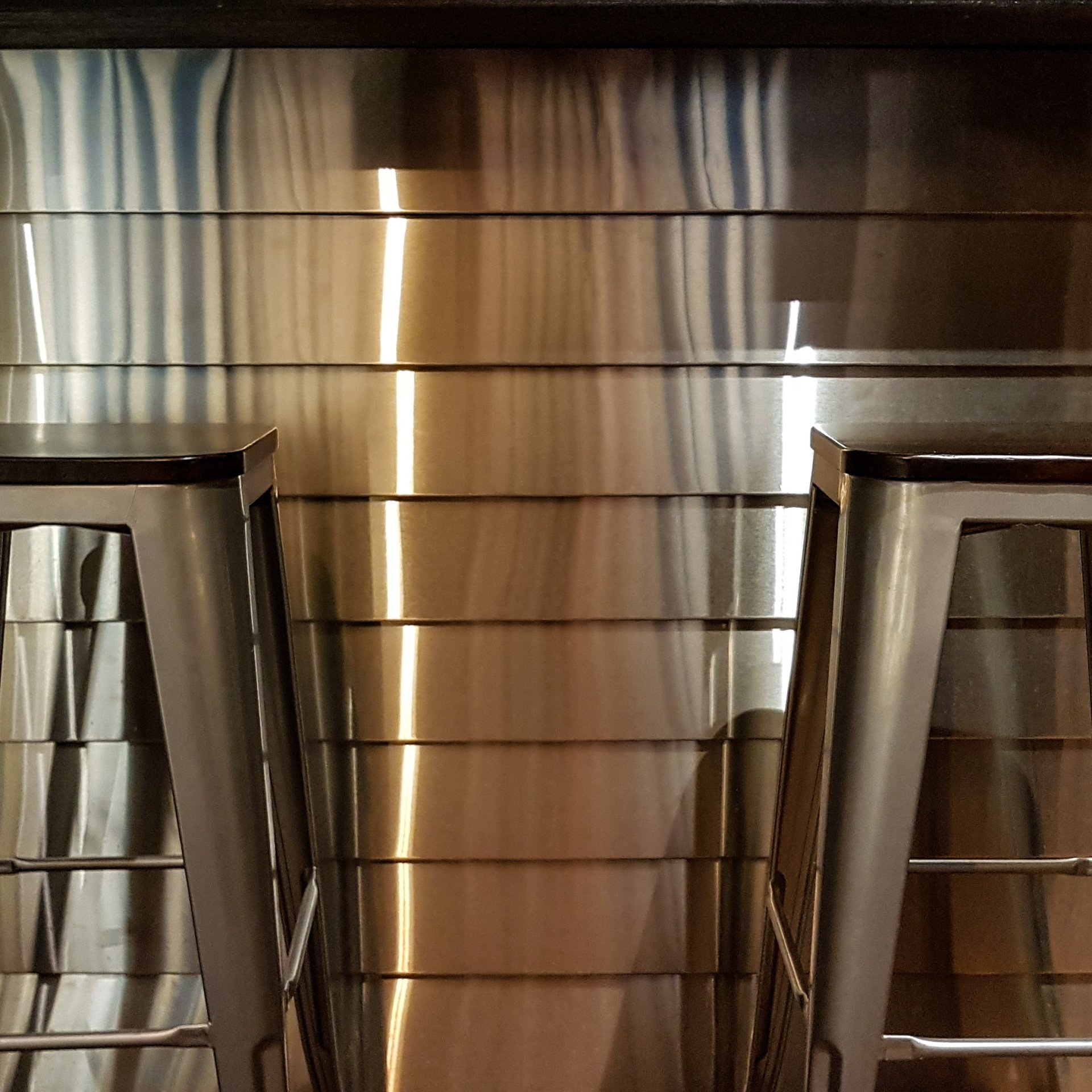 Dos taburetes frente a una pared de acero inoxidable.