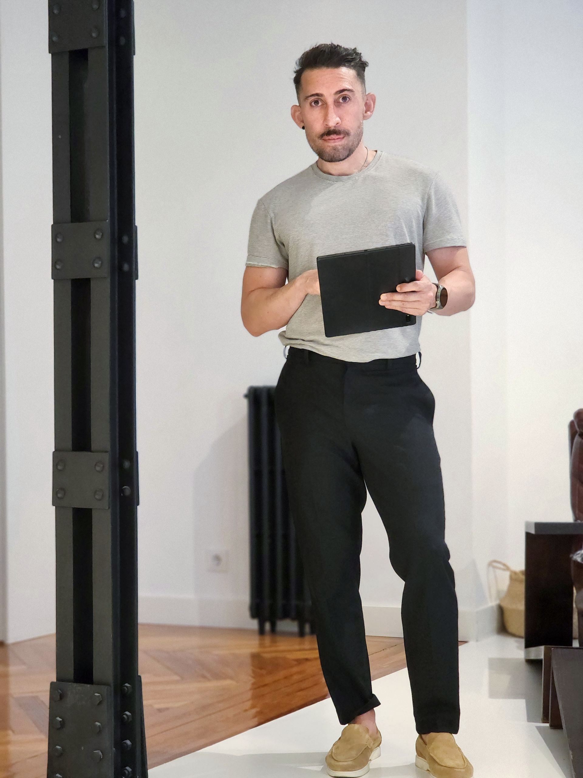 Un hombre de pie en una sala de estar sosteniendo una tableta.