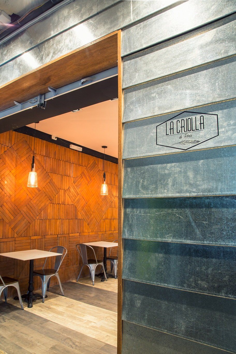 Un restaurante con mesas y sillas y una pared de metal.